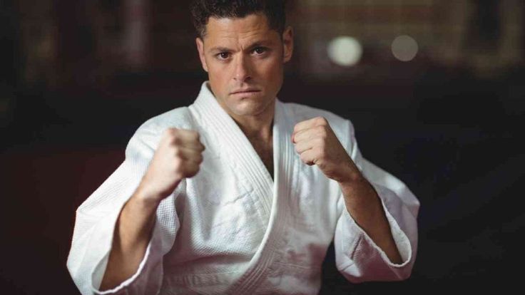 hombre preparado para combate en kimono blanco con fondo oscuro