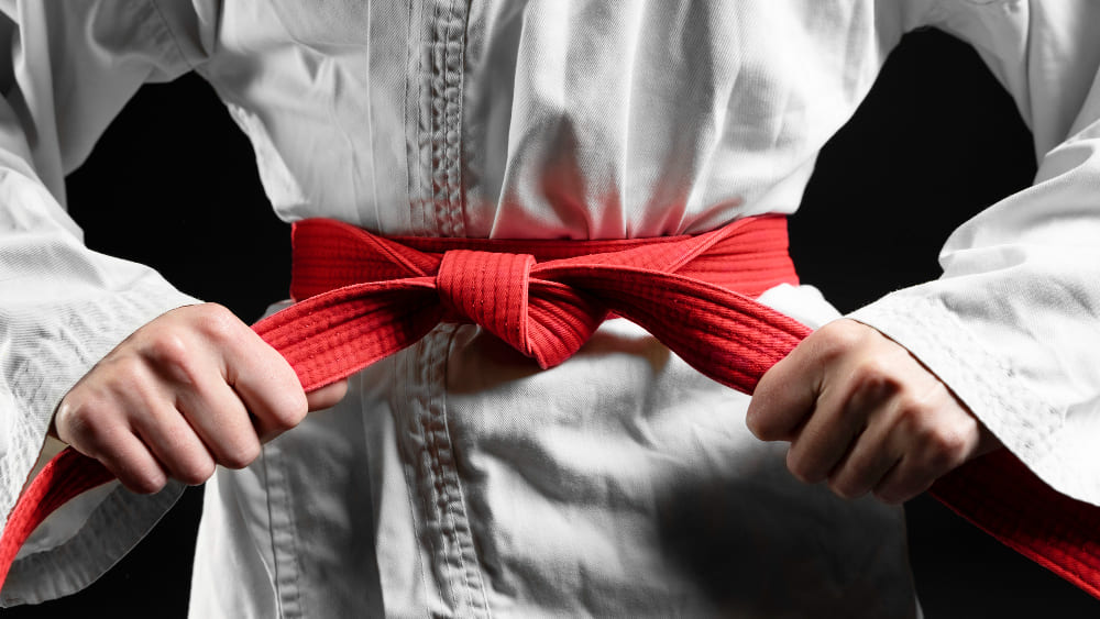 alumno karate atandose cinturon rojo